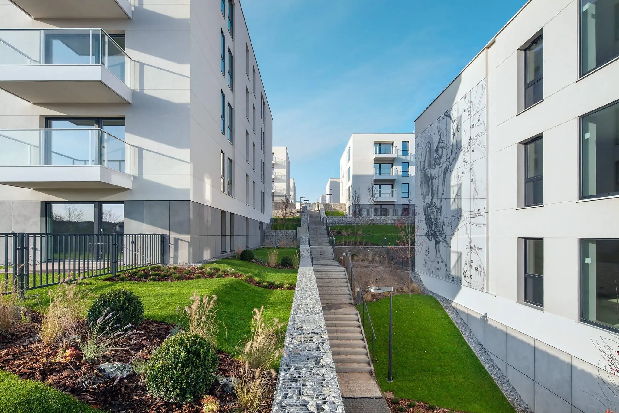 Modern apartment buildings with concrete wall panels, a staircase and greenery on a clear day