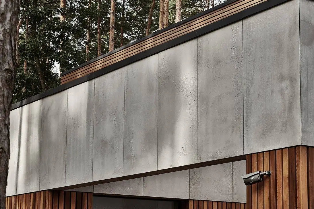 Modern building exterior with concrete panels and wooden accents, surrounded by trees.