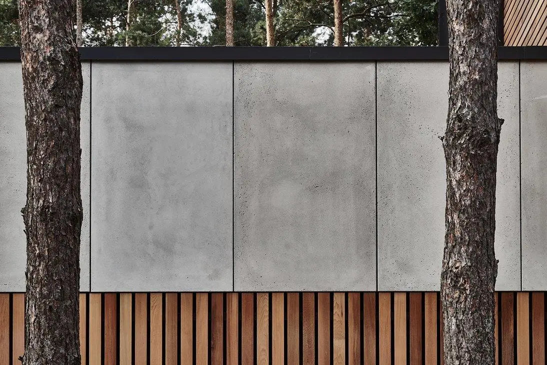 Modern building exterior with concrete panels and wooden slats, surrounded by trees.