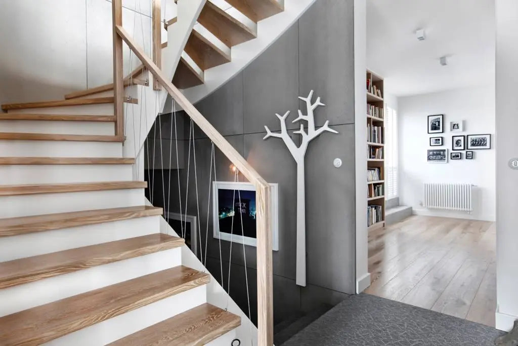 Modern interior with a wooden staircase, a concrete wall, and a bookshelf.