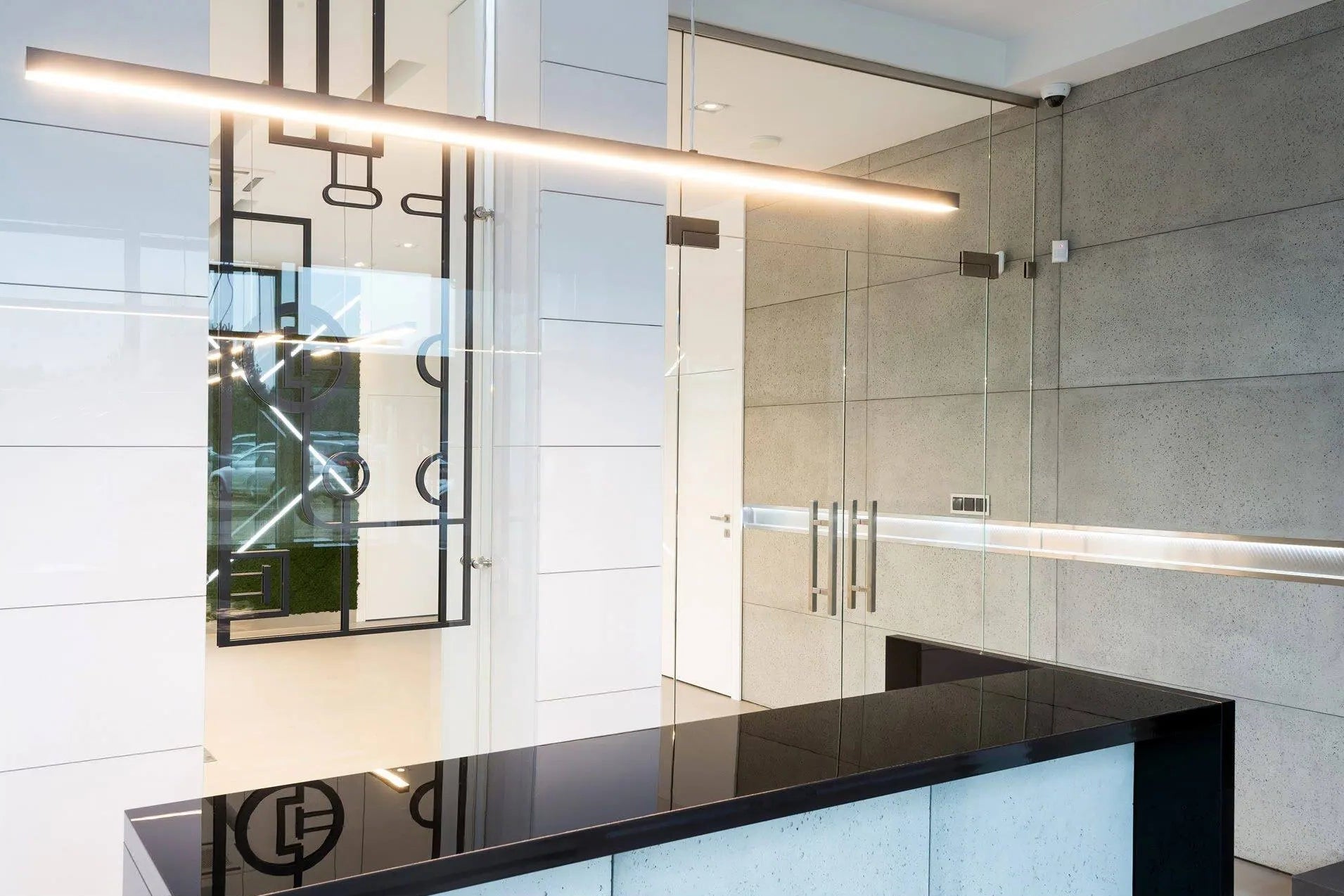 Modern bathroom interior with concrete wall panels, a glass shower enclosure, and a black countertop.