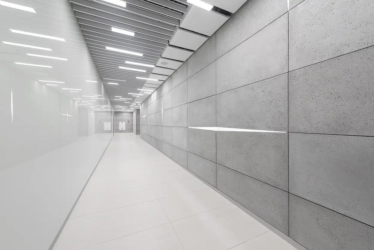 Long, narrow hallway with concrete walls and ceiling lights.