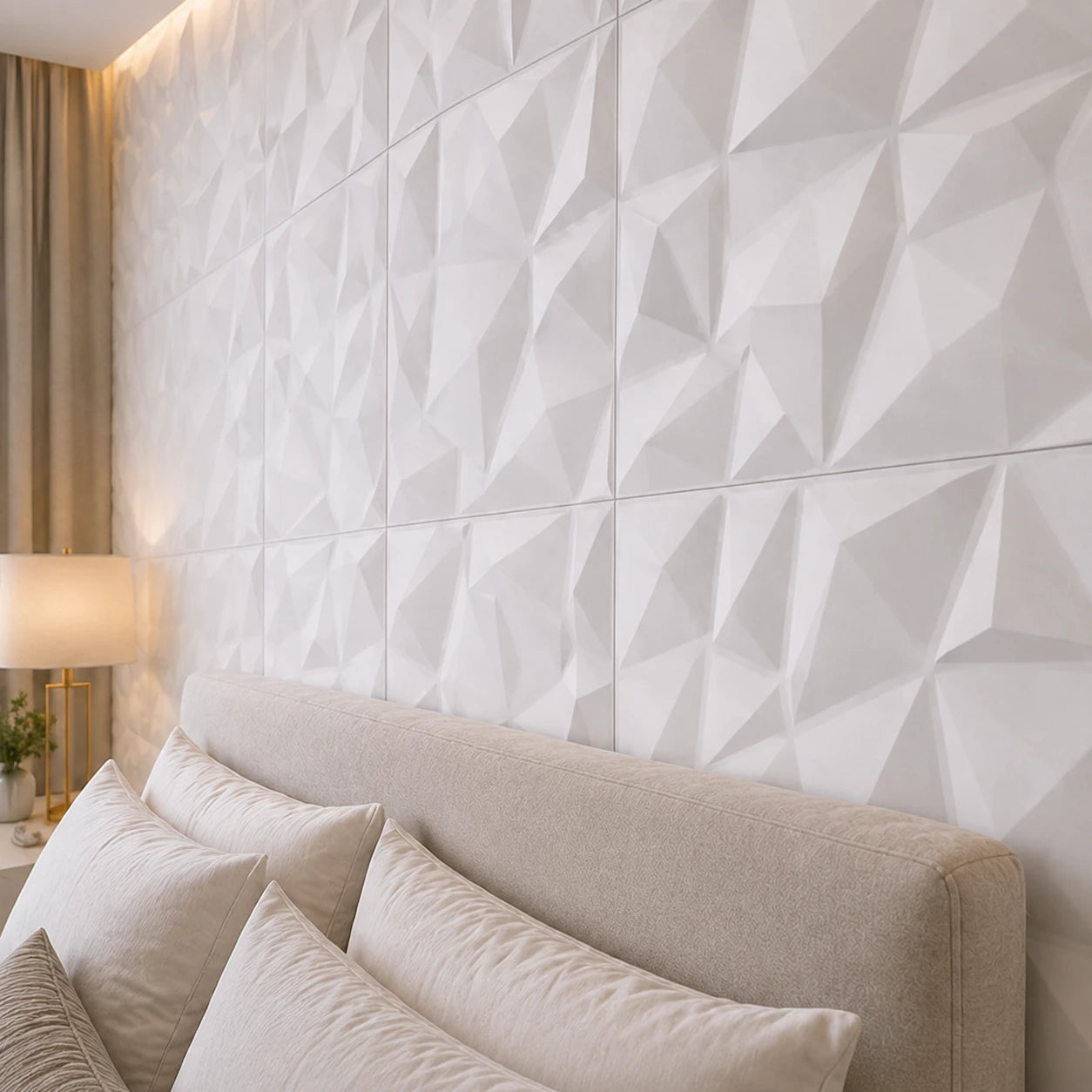 Close-up angled view of white square 3D wall panels with faceted geometric relief, showing the regular grid, panel joints, and part of the upholstered bed for scale