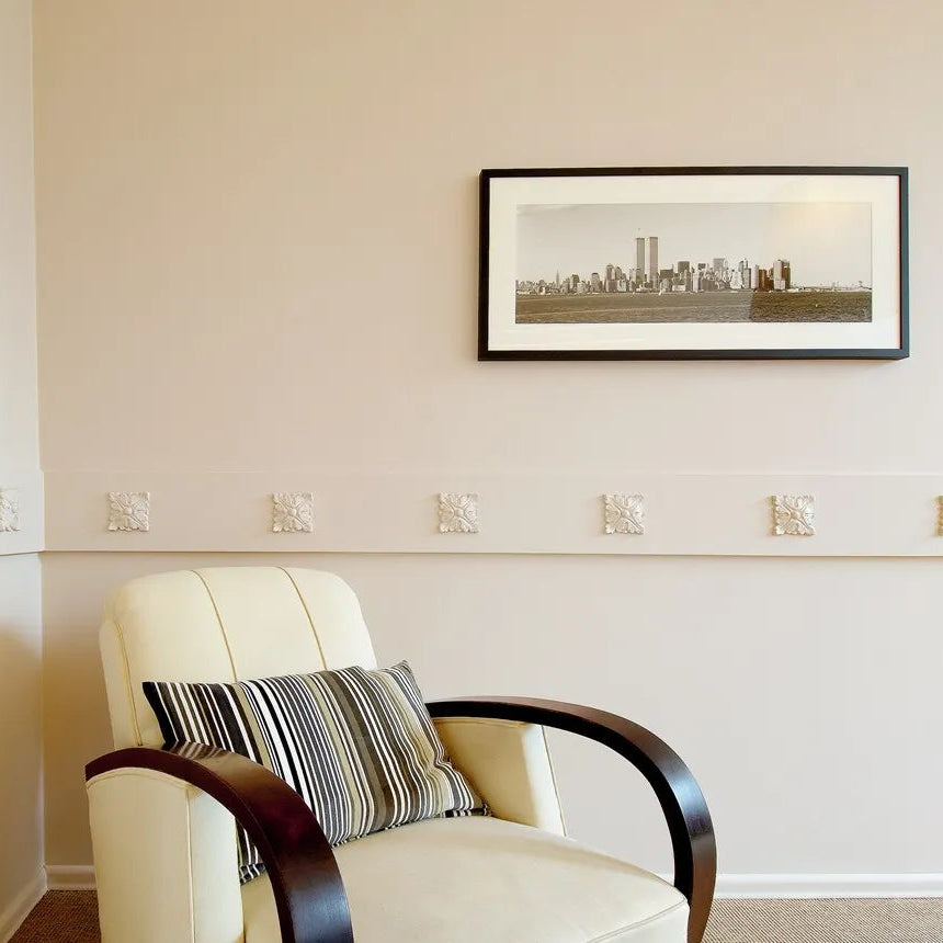 Whit1. e decorative FL3 skirting and wall moulding used in a neutral contemporary living room with an upholstered armchair and framed wall art