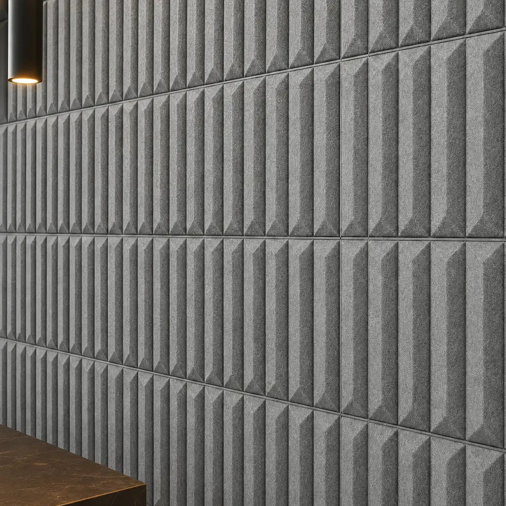 Close-up of grey GROVE 3D acoustic felt wall panels showing the geometric relief, regular seams and textured felt surface