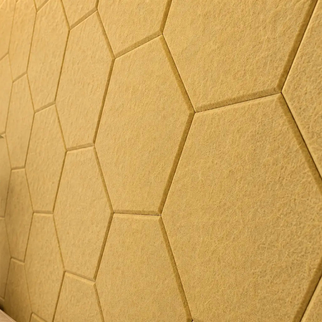Yellow HEXA 3D felt PET wall panels in a stylish living room with a cream sofa, leather armchairs and warm wooden furniture cloes up view