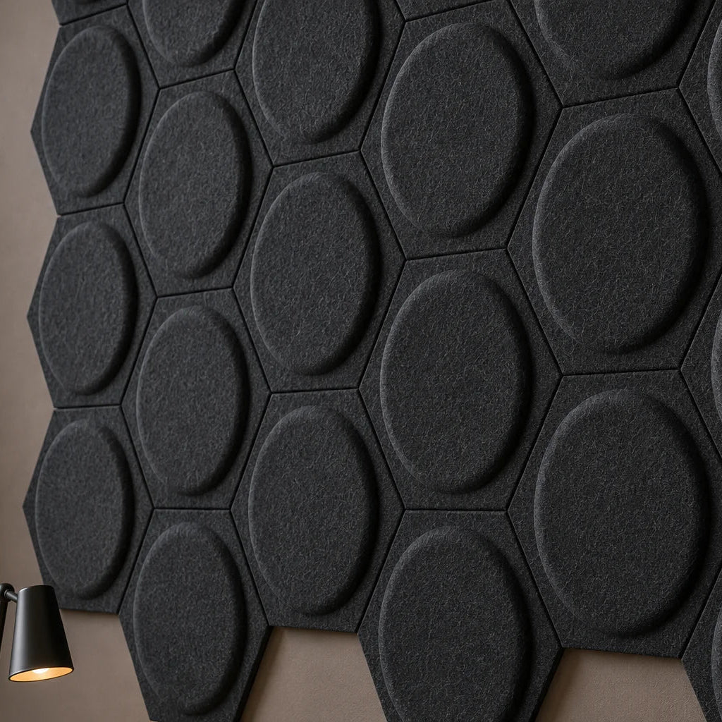 Close-up of black hexagonal felt acoustic panels showing raised circular relief, panel joints and fibrous texture