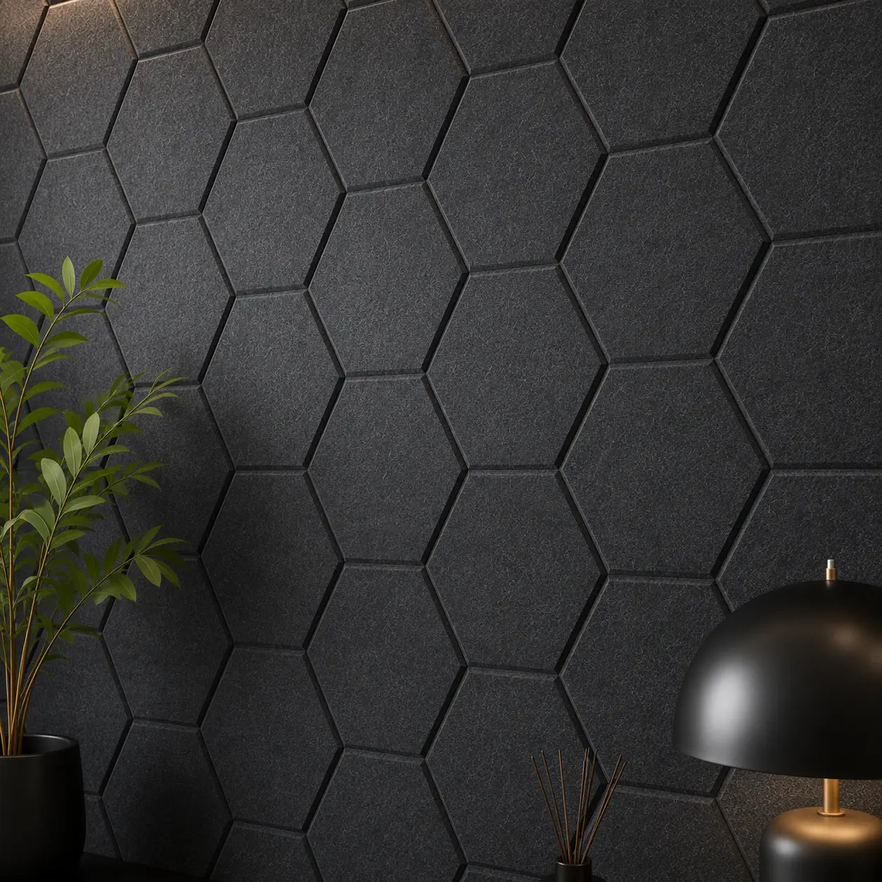 Dark black hexagonal acoustic wall panels mounted on a wall, styled with a green potted plant on the left and a black dome table lamp on the right.