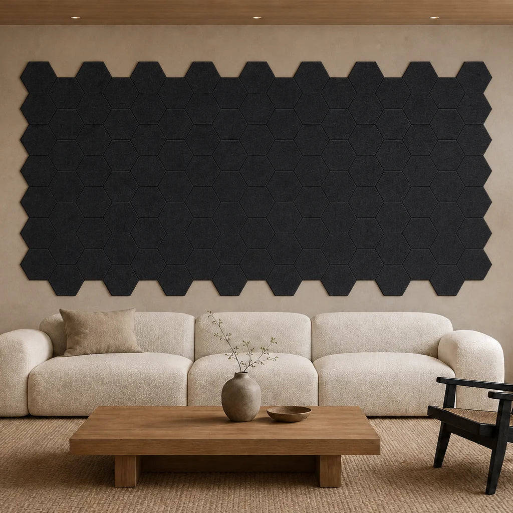 Large installation of flat black hexagonal felt acoustic panels above a cream sofa in a modern living room