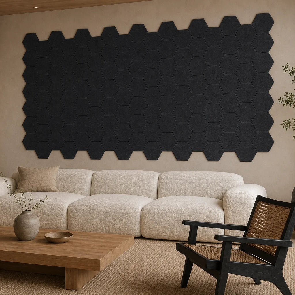 Angled view of flat black hexagonal acoustic panels covering the wall behind a cream sofa
