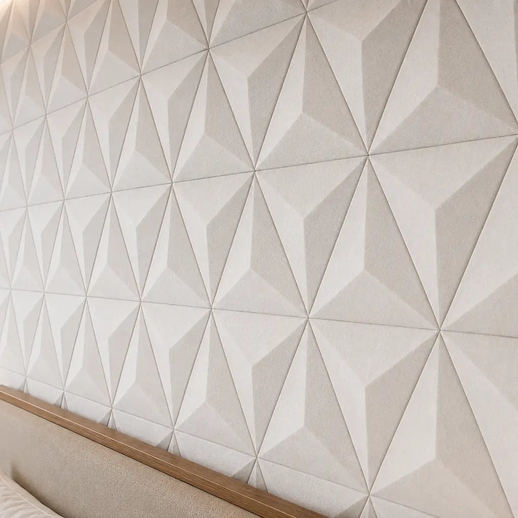 Close-up of white PYRAMID 3D acoustic felt wall panels in a hotel bedroom, showing the raised geometric pattern, soft felt texture and warm side lighting