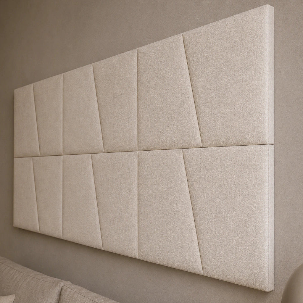 Close-up angled view of cream upholstered wall panels, highlighting their diagonal seams, padded relief, precise joints and textured fabric finish