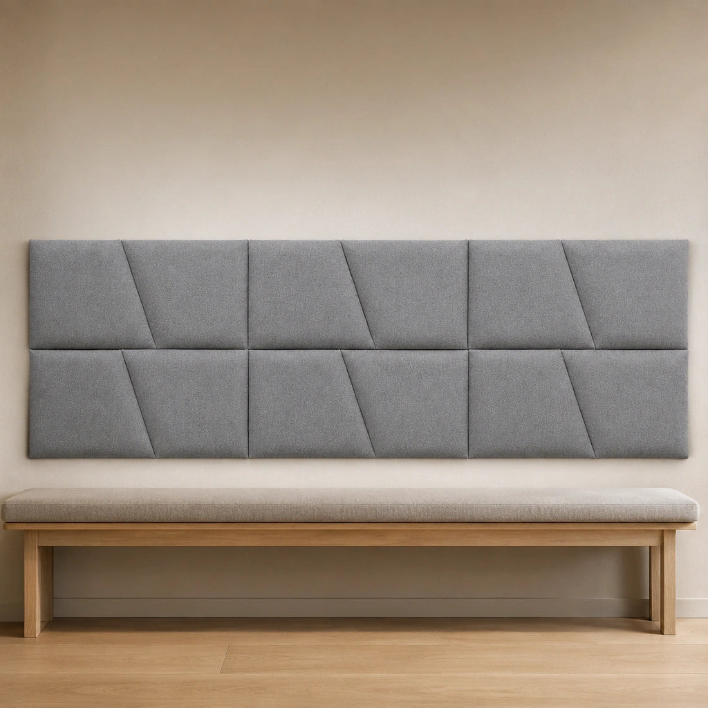 Front view of a large cream upholstered wall panel with geometric diagonal seams, displayed above a neutral sofa in a modern living room
