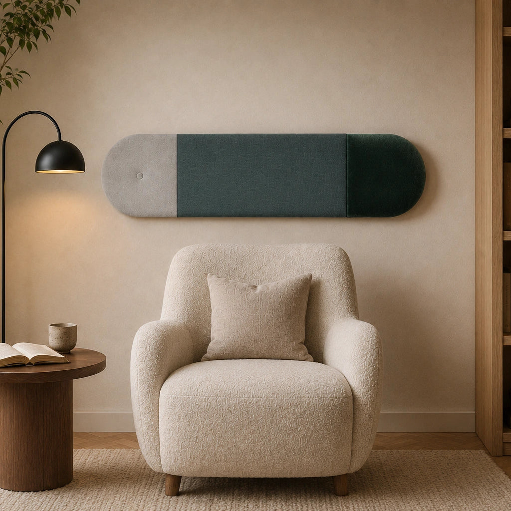 Front view of a three-section upholstered wall panel featuring light grey, muted green and dark green fabrics, displayed above a cream armchair in a cosy reading corner