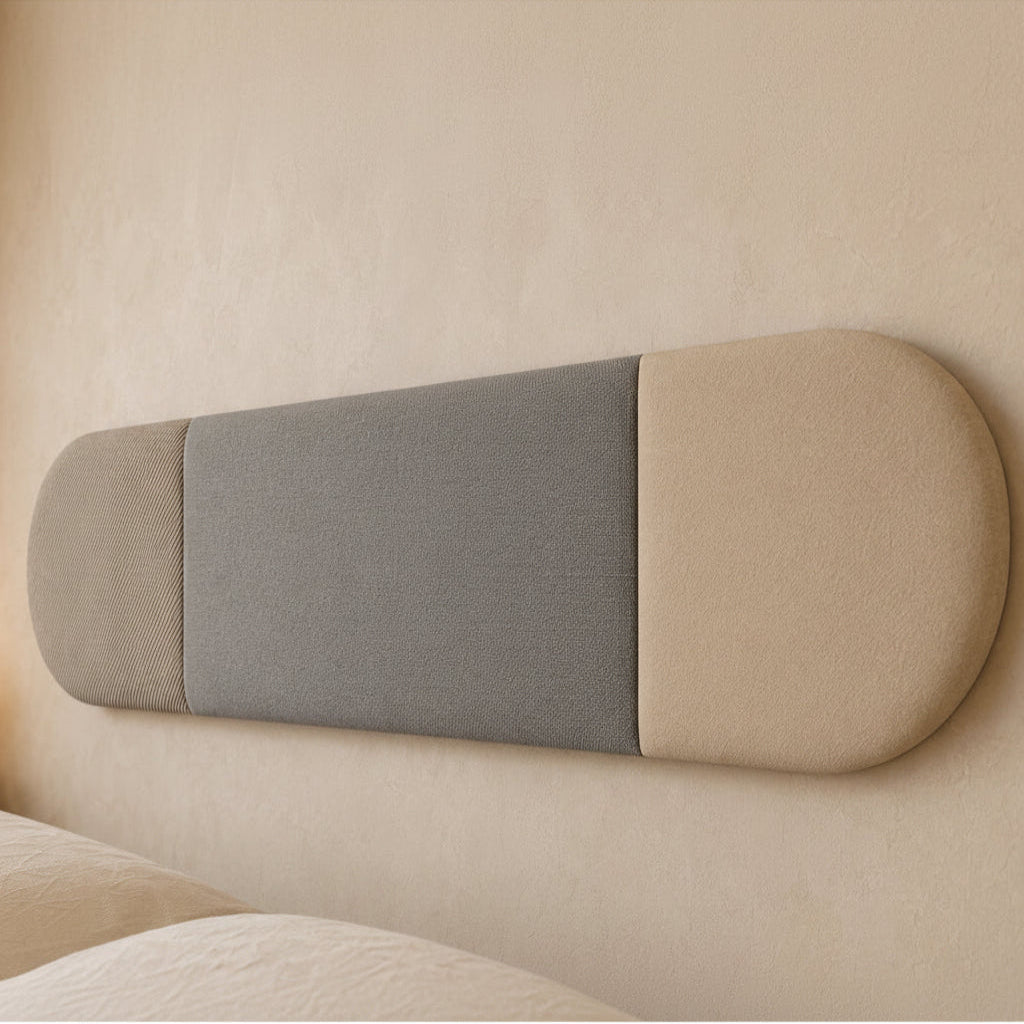 Close-up angled view of a three-section upholstered wall panel, highlighting its rounded ends, vertical seams and contrasting beige and grey fabric textures