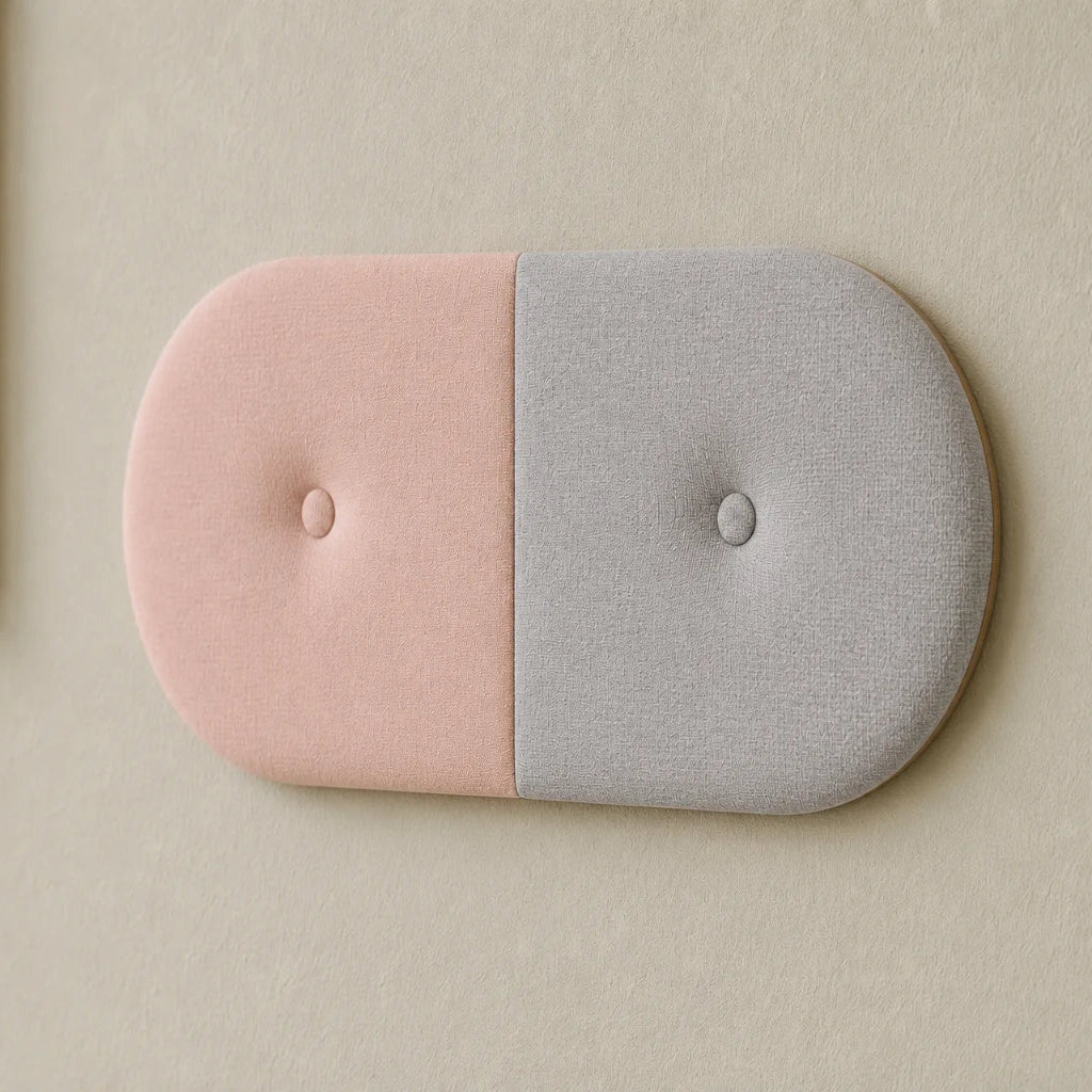 Close-up angled view of a two-tone upholstered wall panel, highlighting its pastel pink and light grey fabrics, central seam, rounded edges and matching button details