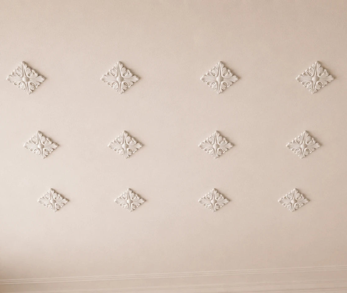 Close-up of decorative white ceiling ornaments in a symmetrical ceiling pattern
