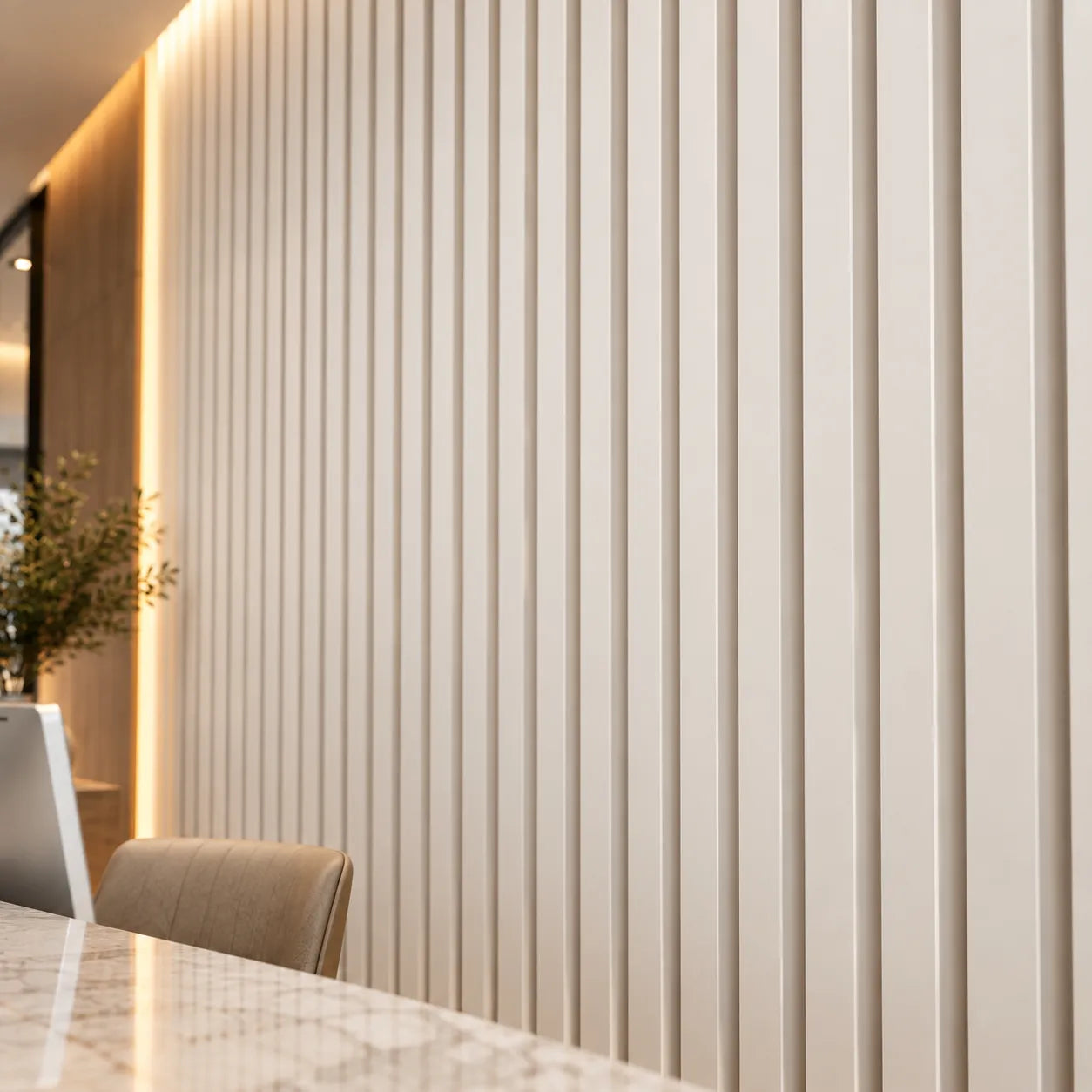 Close view of white Slats 3D gypsum wall panels showing vertical ridges and recessed grooves beside a reception counter