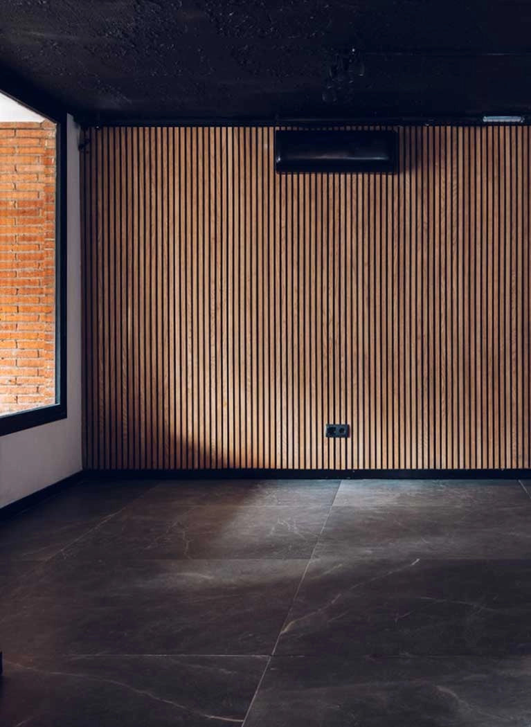 Black wall with Acoustic wood slat wall panelling long textured panels in modern interior Decormania UK