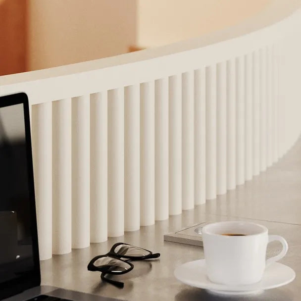 Close-up of white CANELÉ XL FLEX panels along a curved workstation with a laptop and coffee cup
