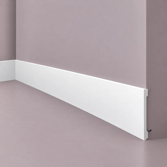 White NMC F20S skirting profile with integrated cable channel, shown installed around an interior wall corner