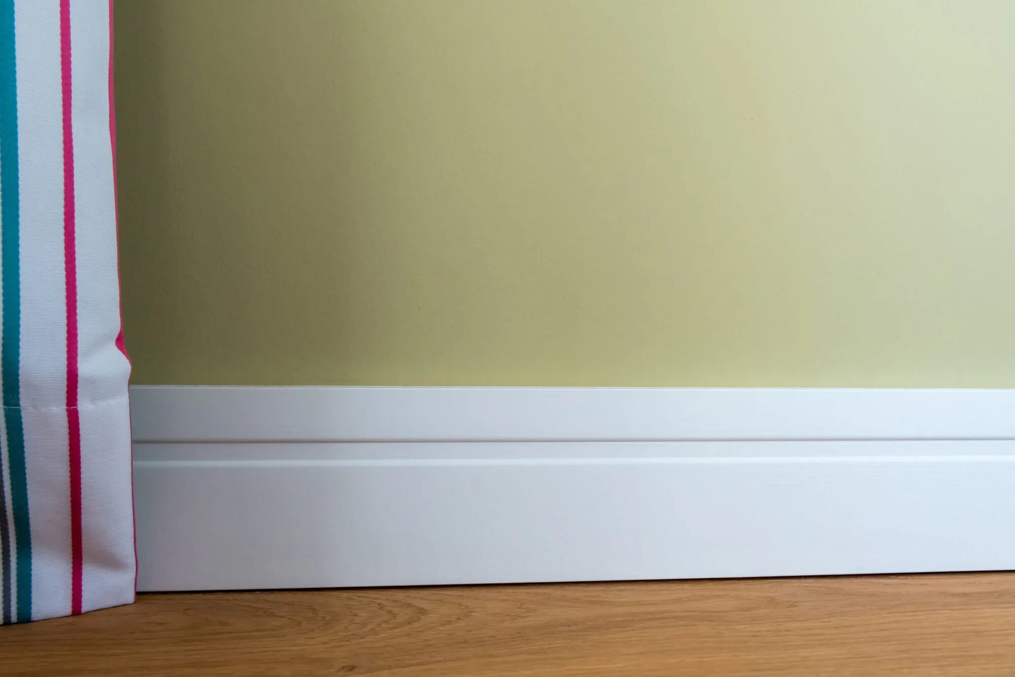 FD11 2M WALLSTYL Skirting Board in a room with green wall and wooden floor | DecorMania UK
