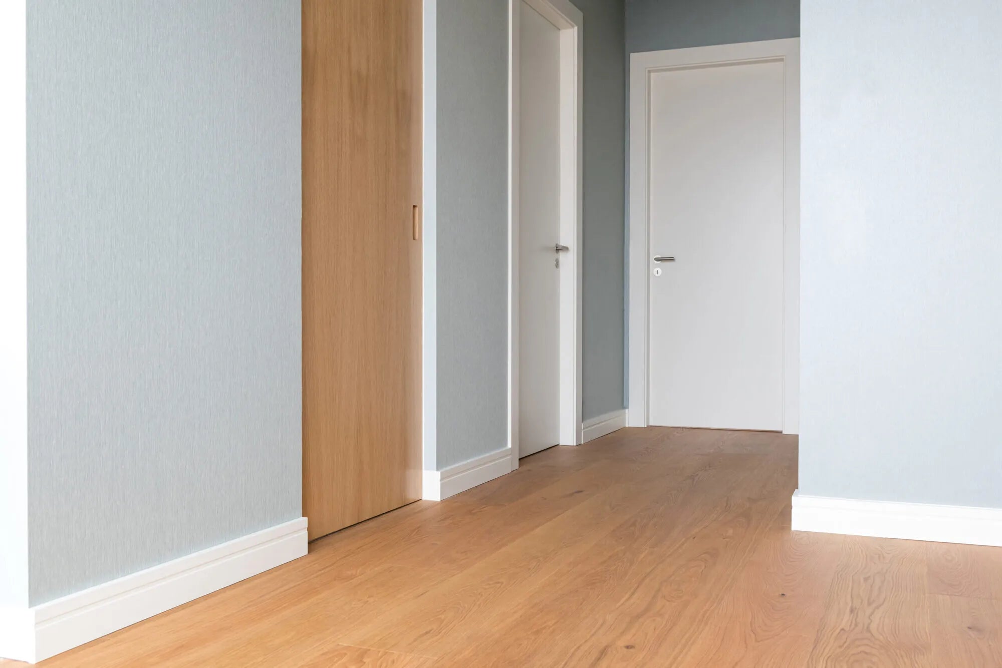 FD11 2M WALLSTYL Skirting Board in a modern hallway with gray wall and wooden floor | DecorMania UK