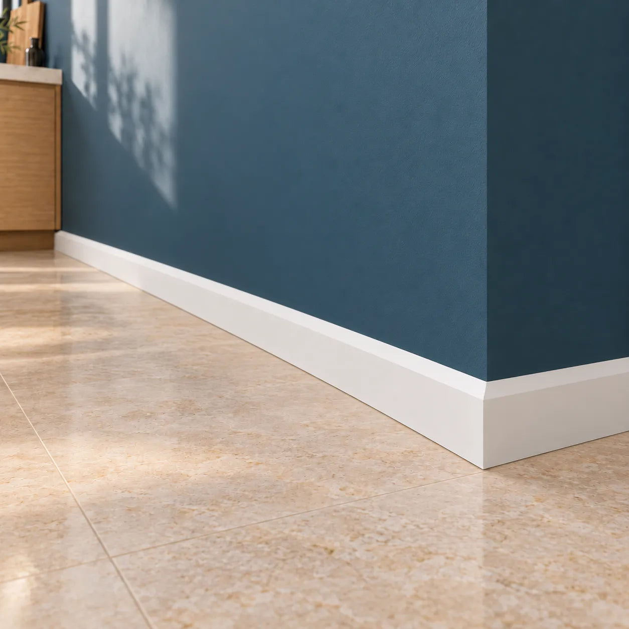 Close-up of white FT1 WALLSTYL skirting board fitted around a blue wall corner