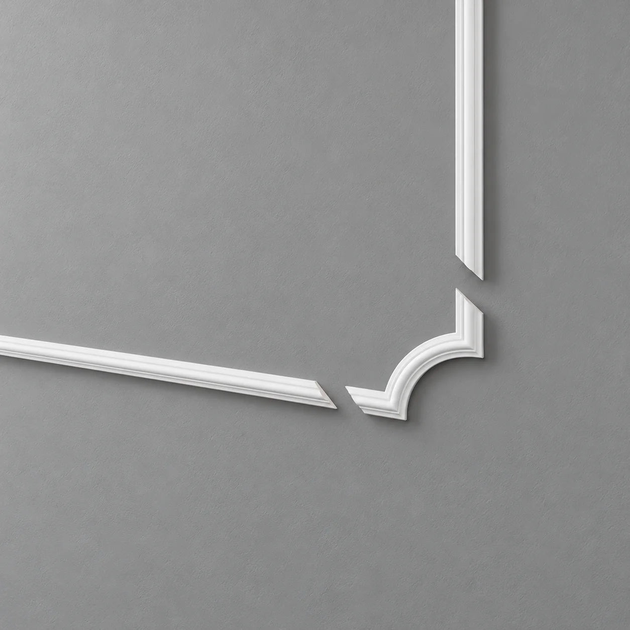 White SP3-4 curved corner moulding with separated straight rails on a grey wall